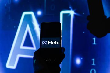 Meta's logo appears on the screen of a smartphone against a blue background. The letters "AI" appear in large print on the background.