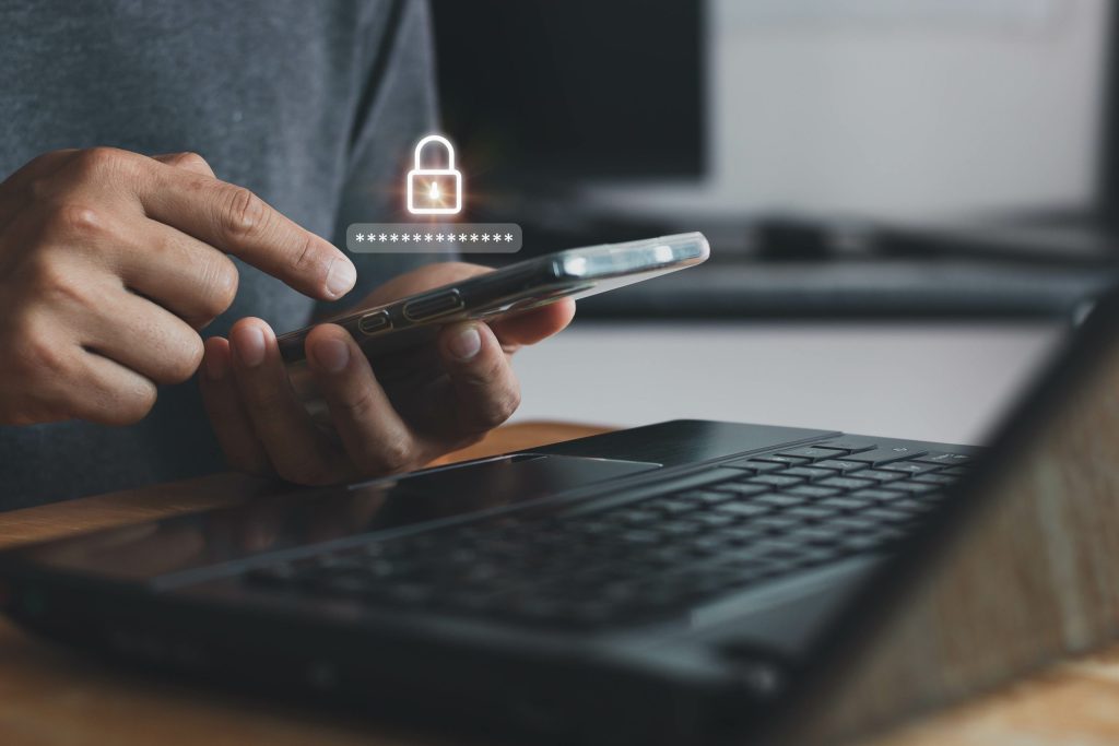 Asian businessman using the smart mobile phone to access on phone with laptop for validate password for biometric two steps authentication to unlock security, Business Technology security Concept