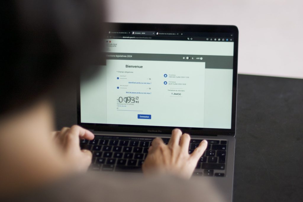 A woman at a laptop follows the steps to vote online in France's legislative elections.